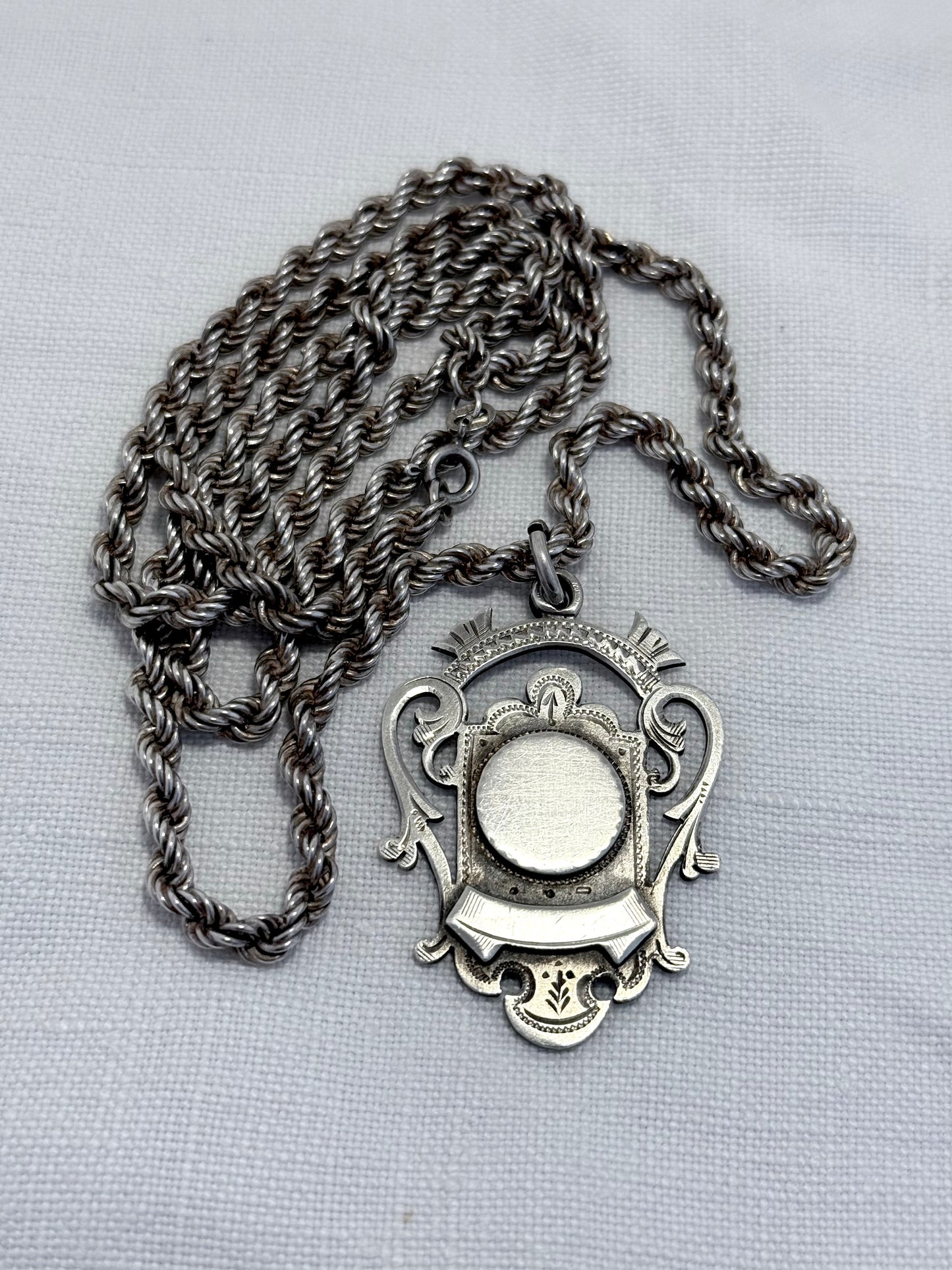 antique Silver fob medallion on thick silver chain necklace on a light gray background